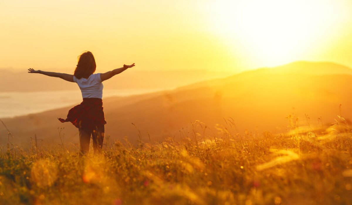 Happy woman standing with her back on sunset in nature iwith open hands 💆♀️ Krása bez výkonu – rituály, ktoré ťa naplnia, nie vyčerpajú